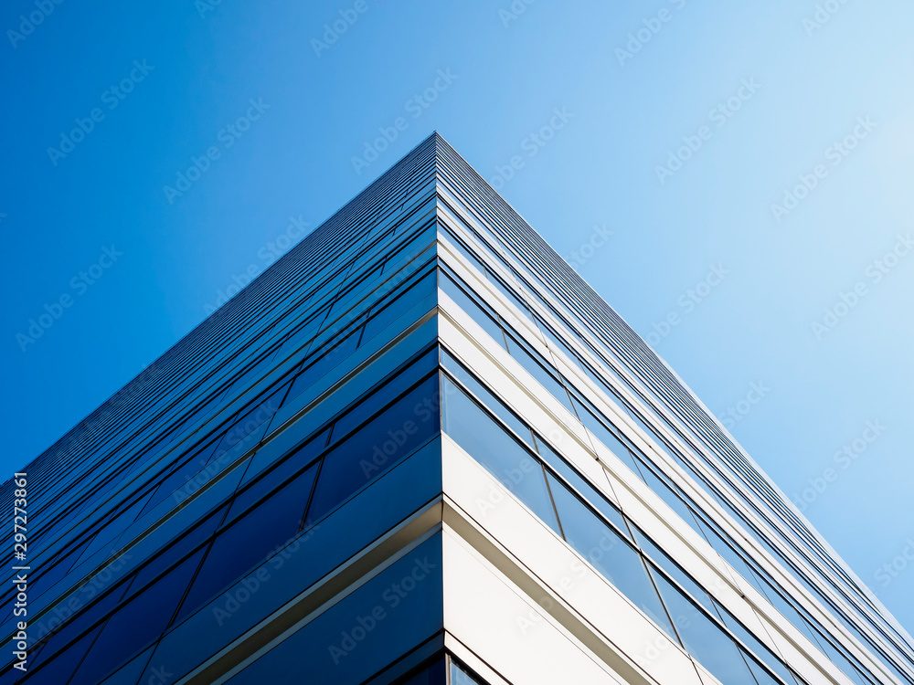 The corner of a glass office tower against blue sky
