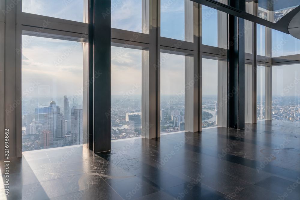 A stone-floored atrium with floor-to-ceiling glass looking out over a city