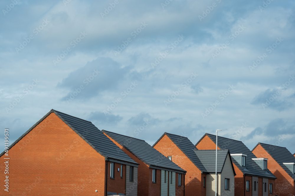 New-build brick homes under a wide sky