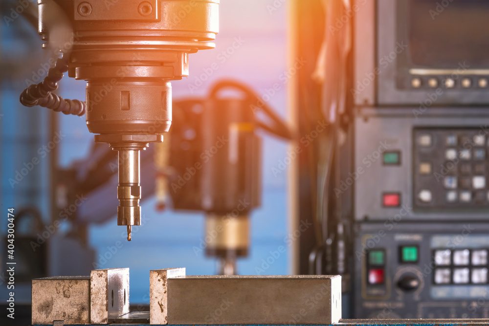 A CNC milling head over a metal workpiece