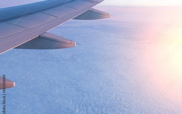 An aircraft wing above the clouds at sunrise