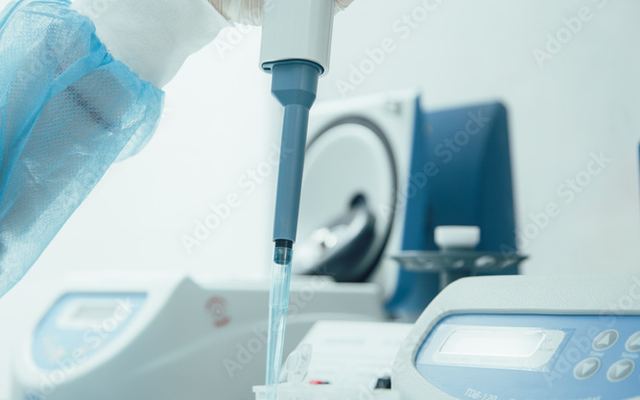 A pipette dispensing into a laboratory tray