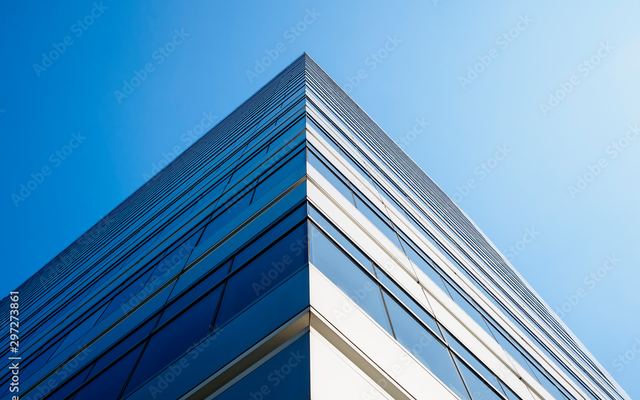 The glass facade of an office building against a clear sky